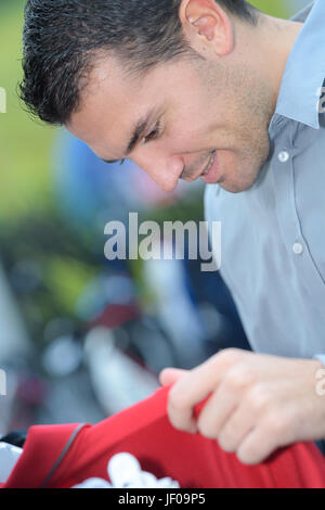 Uomo bello scegliendo t-shirt in negozio di abbigliamento Foto Stock