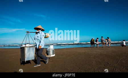 I turisti e i fornitori di prodotti alimentari sul retro spiaggia, Vung Tau, Vietnam Foto Stock