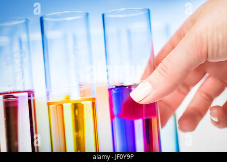 Donna di mano scegliendo un tubo di test con viola liquido all'interno. Le prove di laboratorio e di vetro. Foto Stock