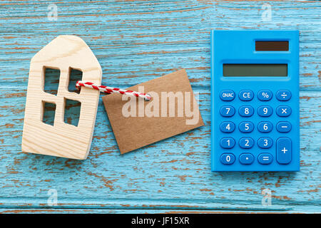 Casa in legno con la calcolatrice e vuoto etichetta di carta per alloggiare il concetto di prestito Foto Stock