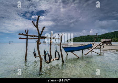 Bella blu canoa e rustico, altalene artigianale costruito sopra le acque chiare del Annora beach, in Karimunjawa. Foto Stock