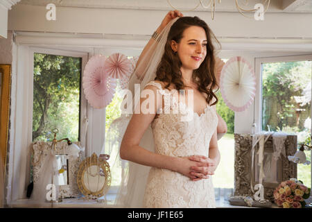 Una sposa per essere, una giovane donna cercando su abiti da sposa in uno specialista boutique nuziale. Foto Stock