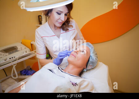 Il medico fa una donna paziente esthetician procedure sulla faccia Foto Stock