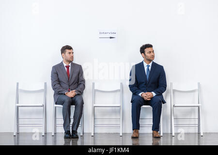 Uomini d'affari in giacca seduti su sedie in bianco in sala d'attesa. business meeting Foto Stock