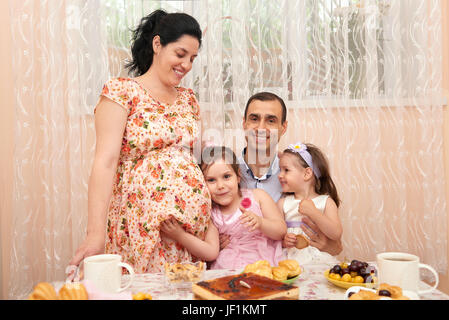 La grande famiglia bere il tè nella sala da pranzo, la donna in stato di gravidanza Foto Stock