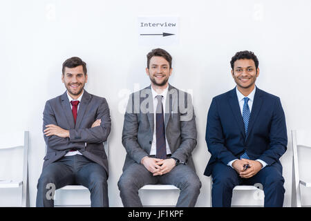 Uomini d'affari in giacca seduti su sedie in bianco in sala d'attesa. business meeting Foto Stock