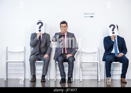 Gli imprenditori seduti in coda in attesa per l'intervista, tenendo i punti interrogativi in ufficio, la concezione di business Foto Stock