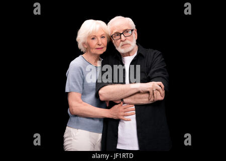 Malinconici senior abbracciando la donna uomo isolato su nero Foto Stock