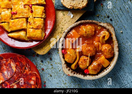 Alta angolazione di alcune piastre con differenti spagnolo affettati e tapas, come la frittata spagnola, polpette con seppie o affettato chorizo su un Foto Stock