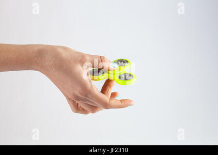 Mano femmina giallo holding agitano: spinner isolato su sfondo bianco con spazio di copia Foto Stock