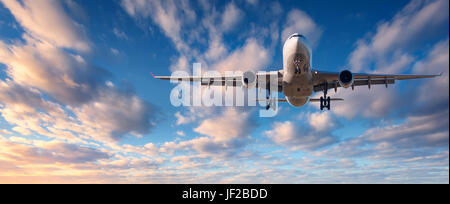 Atterraggio aereo. Paesaggio con bianco aereo passeggeri vola nel cielo blu con nuvole al tramonto colorato. Sfondo di viaggio. Airli passeggero Foto Stock