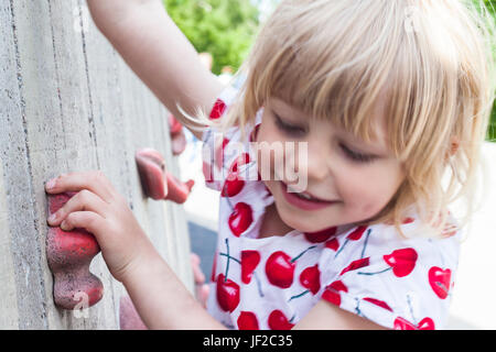 Ragazza salendo sulla parete di arrampicata Foto Stock