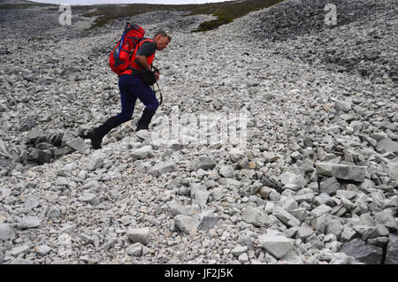 Maschio di Lone Hill Walker salendo sul ghiaione versanti sulla montagna scozzese Corbett Beinn una funzione Oir uno dei tre pappe del Giura, Foto Stock