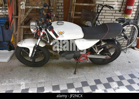 Un simpatico Pezzo adesivo sul serbatoio di gas di un motociclo bianco in Taiwan parcheggiata vicino all'appartamento. Foto Stock