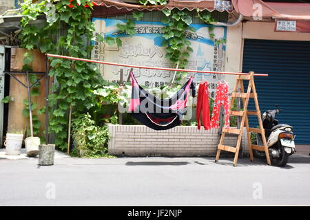 Una coperta e alcuni pigiami appesi lungo la strada a un palo per tutti a vedere come passano. Taiwan Foto Stock