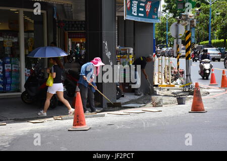 Donna lavoratore edile lavorando duro nella calura estiva di 93 F e indossando un cappello rosa vicino al parco Xinzhuang. Foto Stock