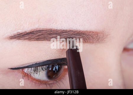 Close-up donna utilizzando una matita per le sopracciglia per il trucco Foto Stock