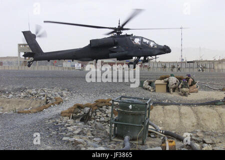 041012-M-6508B-512 Marines dal Marine Wing Support Squadron 473 anatra per coprire da battenti le pietre come un AH-64 Apache elicottero atterra vicino a inoltrare una base operativa Orgun-E in Afghanistan il 12 ottobre 2004. DoD foto di Staff Sgt. Rusty Baker, U.S. Marine Corps. (Rilasciato) Foto Stock