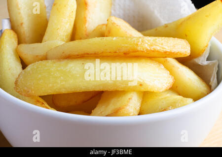 Close up (macro) di una ciotola riempita con chip (patatine fritte) con della carta assorbente. Foto Stock