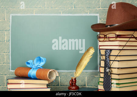 Jesting insolita insegnante, libri, quill penna, scorrere prima di lavagna con spazio di copia Foto Stock
