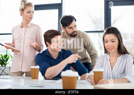 Un gruppo di giovani uomini di affari che guardando il collega per piccole riunioni aziendali Foto Stock