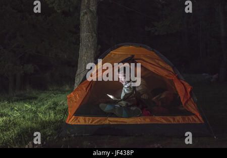 L'uomo guarda il suo smartphone in una tenda. Foto Stock