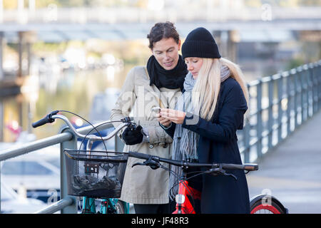 Le donne con le biciclette guardando al telefono cellulare Foto Stock