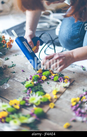 Fioraio effettuare decorazioni di fiori con lettere e colla. In interni luce naturale shot con piccole profondità di campo Foto Stock