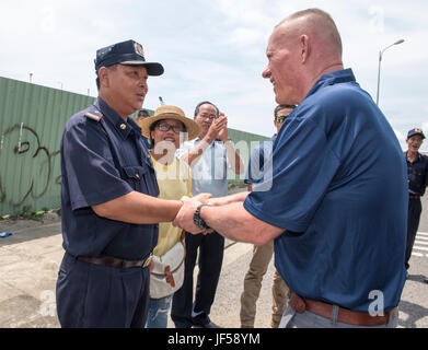 170526-N-OU129-190 KHANH Hoa in Vietnam (26 maggio 2017) DEGLI STATI UNITI Marine Corps Lt. Gen. Lawrence Nicholson, Comandante generale III Marine forza expeditionary, presenta una sfida moneta locale a una Nha Trang alle forze di sicurezza membro del team durante il partenariato del Pacifico 2017 Khanh Hoa, 26 maggio. Pacific Partnership è il più grande annuale multilaterale di assistenza umanitaria e di soccorso in caso di catastrofe preparazione missione condotta nel Indo-Asia-pacifico e mira a migliorare il coordinamento regionale in settori quali medico predisposizione e preparazione per le catastrofi provocate dall'uomo e naturali. (U.S. Navy foto di comunicazione di massa Foto Stock