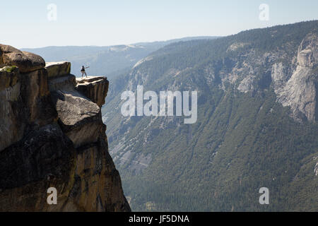 Un visitatore di Yosemite National Park sorge su una sporgenza di roccia a Taft Point. Questa battuta ad una quota di circa 7.500 piedi, sorge a migliaia di metri sopra la valle di Yosemite. Foto Stock