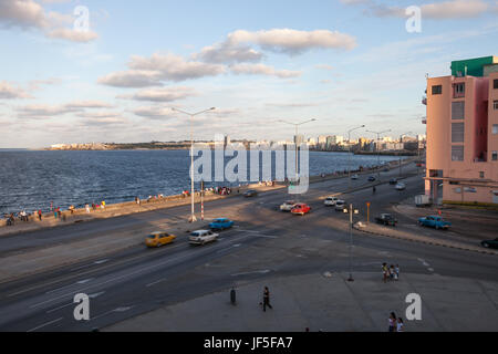 Traffico di persone e di veicoli si muovono attraverso un ampio incrocio vicino al Malecon, una passeggiata lungo il lungomare di l'Avana. Foto Stock