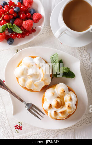 Limone tortine di meringa, frutti di bosco e caffè sul tavolo. close-up. vista verticale da sopra Foto Stock