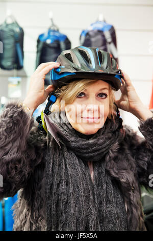 Donna cerca sul casco per bicicletta Foto Stock