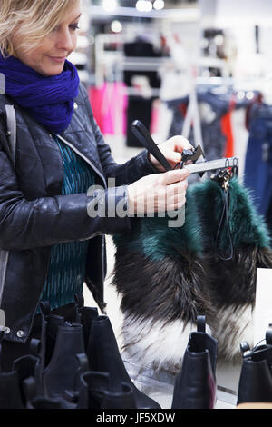 Donna controllo fur sciarpa in negozio Foto Stock