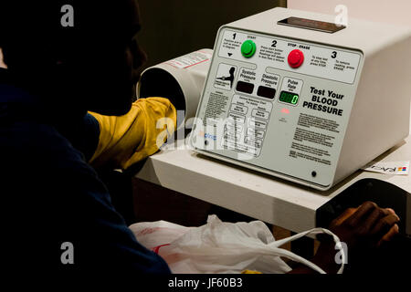 Giovane uomo nero (afro-americani, americano africano, maschio) controllando la pressione del sangue sul monitor della pressione del sangue - USA Foto Stock