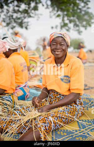 Le donne da un tessitore cooperativa tessere tradizionali cesti di paglia insieme nella Upper East Regione, Ghana. Foto Stock