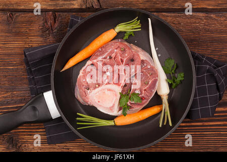 Ossobuco crudo ingredienti nella coppa sul tavolo di legno, vista dall'alto. La cucina gastronomica. Foto Stock