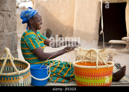 Una donna si intreccia tradizionali cesti di paglia in Upper East Regione, Ghana. Foto Stock