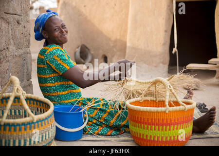 Una donna si intreccia tradizionali cesti di paglia in Upper East Regione, Ghana. Foto Stock