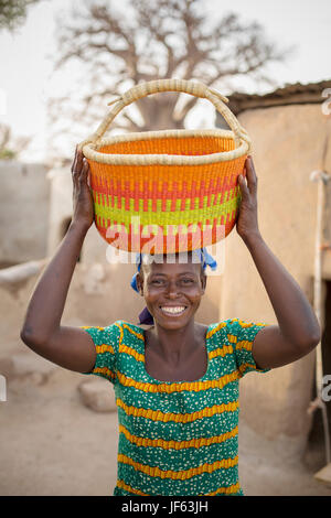Una donna che tiene un tradizionale cestello di paglia in Upper East Regione, Ghana. Foto Stock