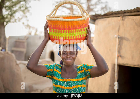 Una donna che tiene un tradizionale cestello di paglia in Upper East Regione, Ghana. Foto Stock