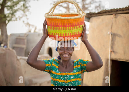 Una donna che tiene un tradizionale cestello di paglia in Upper East Regione, Ghana. Foto Stock