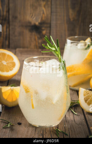 Estate rinfreschi. Detox acqua. Limonata. Tonic con ghiaccio, limone e rosmarino, su un vecchio rustico in legno tavolo. Spazio di copia Foto Stock