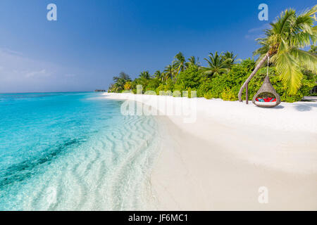 Una perfetta spiaggia tropicale. Amaca romantica o di rotazione sulla spiaggia di sabbia bianca e palme sotto il cielo blu. Di ispirazione vacanze estive e concetto di vacanza Foto Stock