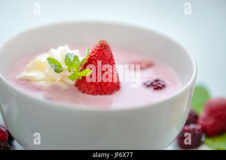 Fresca zuppa di berry closeup con Fragola, foglia di menta e della crema di latte Foto Stock