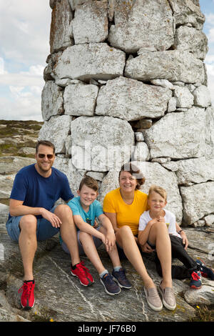 Famiglia seduta mediante la costruzione di pietra Foto Stock