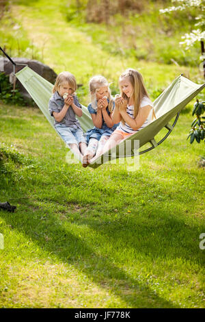 Tre ragazze in seduta amaca holding polli giovani Foto Stock