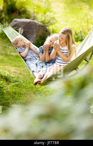 Tre ragazze in seduta amaca holding polli giovani Foto Stock