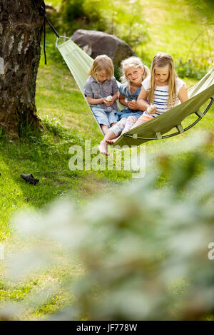 Tre ragazze in seduta amaca holding polli giovani Foto Stock