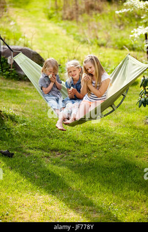 Tre ragazze in seduta amaca holding polli giovani Foto Stock